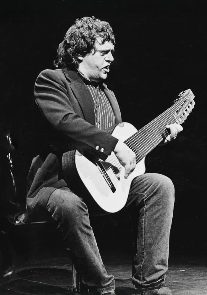 Fred Åkerström sjunger på scen med en flersträngad gitarr.
